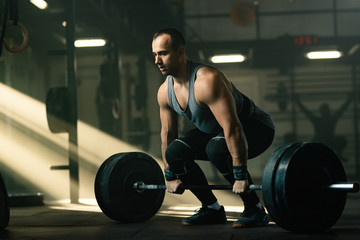 Muscular build man practicing deadlift while exercising in a gym.