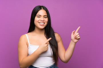 Fototapeta premium Young teenager Asian girl over isolated purple background pointing finger to the side