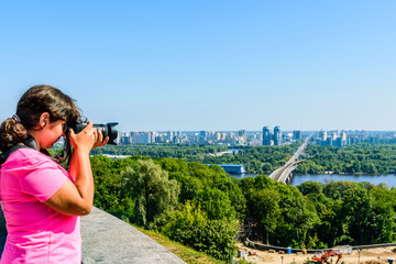 Young woman taking a photo of Kiev cityscape and river Dnieper