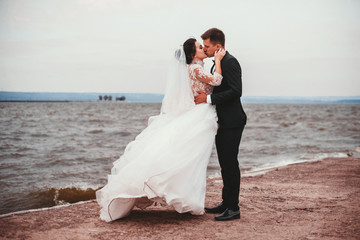 Wedding couple kissing near blue sea