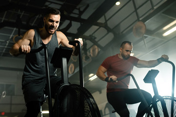 Athletic man making an effort while exercising on stationary bike in a gym.