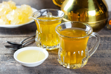 Oriental tea with honey and oriental sweets navat on wooden table background. Ramadan drink