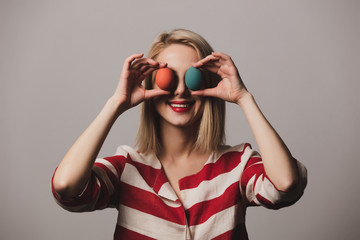girl holds Easter eggs on grey background