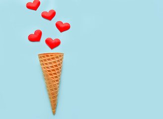 Ice cream waffle cones and hearts on paste blue background, top view, flat lay. selective focus. Valentine's Day. Many hearts fall in of the waffle cones. Valentine's day. Love. Copy space.