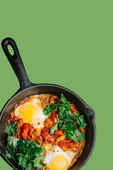 Fried eggs on a pan with tomatoes and parsley leaves. Top view.