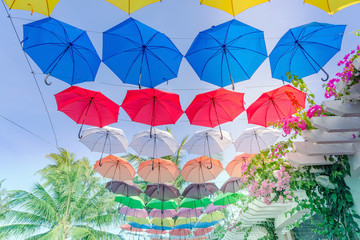 Fototapeta na wymiar Street decorated with colorful umbrellas hanging on top side in the sky. Colorful umbrellas background.