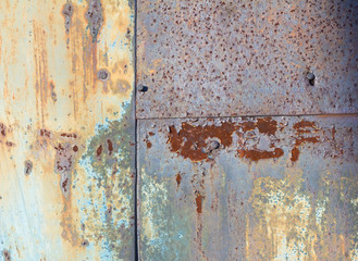 Brown and yellow rust on the metal sheet with the remnants of blue paint. Rusty abstract texture. Rust through the paint.