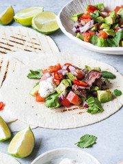 Tortillas with vegetables and beef steak slices. Avocados, tomatoes, red onions and meet with cilantro and lime juice in tortillas. Mexican food.