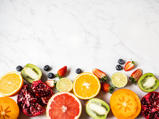 Multicolored seasonal healthy natural fruit border with persimmon, blueberries, orange, kiwi, strawberries, grapefruit, pomegranate, orange slices.
