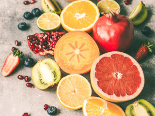 Fototapeta na wymiar Multicolored seasonal healthy natural fruit composition with persimmon, blueberries, orange, kiwi, strawberries, grapefruit, pomegranate, orange slices. Top view
