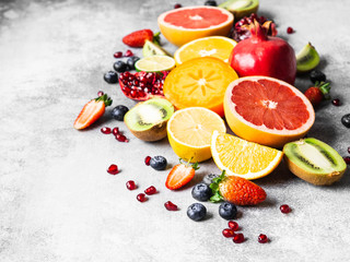 Multicolored seasonal healthy natural fruit composition with persimmon, blueberries, orange, kiwi, strawberries, grapefruit, pomegranate, orange slices. Copy space