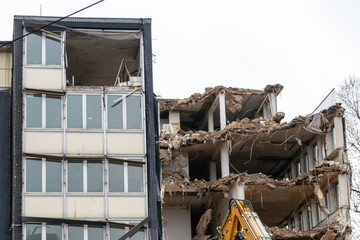 Nach einem Erdbeben eingestürztes Gebäude ist zerstört und wird mit Abrissbagger abgerissen und durch neue Architektur ersetzt zur Stadtentwicklung und Gestaltung