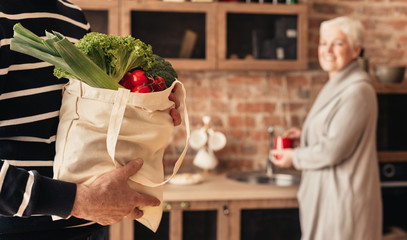 Senior couple unpacking fabric bag with organic food