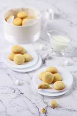 Little round Vanilla Butter Cookies, round box, plate, coffee, light marble background.