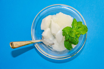White ice cream sorbet with fresh mint leaves in glass  on blue background, refreshing summer diet dessert, top view copy space.