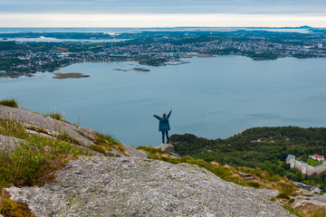 Young woman is standing on the cliff with the beautiful view at the Dalsnuten mountains, Rogaland county, Norway