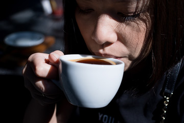 Young pretty woman drinking coffee in Cafe shop interior with blur background
