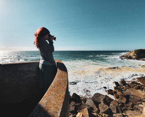 One red haired female photographer taking photos from a beach viewpoint, overlooking the Atlantic...