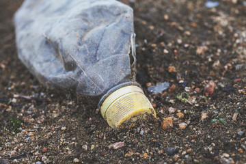 Obraz premium environmental pollution, ecological problem, plastic bottle on the ground, waste, earth, ocean pollution