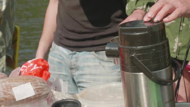 Close up view. Hand of man pour hot tea from thermos in cup.