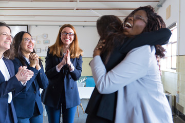Coworkers greeting female colleague in office. Group of happy multiethnic coworkers clapping hands...