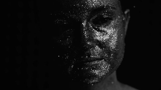 Glitter makeup art. Fashion photography. Tender woman with silver shimmering face skin.