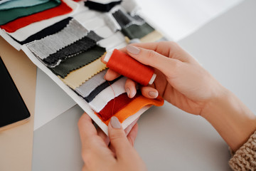 Image of hands on the desktop with nicks in hands and a palette of colors for fabric, designer...