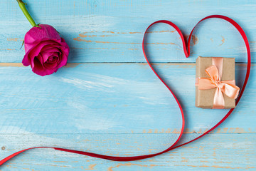 Heart shaped ribbon and gift box on a blue wooden background. Valentine's Day Gift