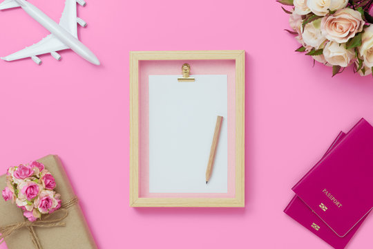 Mockup picture frame for travel with valentines day & love season background concept. Top view of mock up photo frame with craft gift box, passport, sea shell, airplane model on pink background.