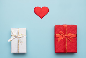 Romantic concept for Valentine`s Day. Flat lay. red heart with red and white gift boxes on a blue background. Romantic concept. Copy Space