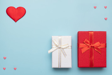 Romantic concept for Valentine`s Day. Flat lay. Pattern of pink and red hearts with red and white gift boxes on a blue background. Romantic concept. Copy Space