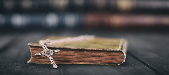Holy Bible, Christian cross necklace on a wooden background.