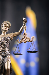 Scales of Justice, Justitia, Lady Justice in front of the European Union flag in the background.