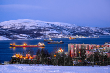 Murmansk, Russia - January, 5, 2020: Non-freezing seaport in the city of Murmansk in winter. The picture was taken at 2 p.m. in natural light at the height of a polar night - obrazy, fototapety, plakaty