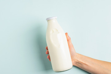 Female hand holds milk or white milk drink in a glass bottle on white background. Healthy eating...