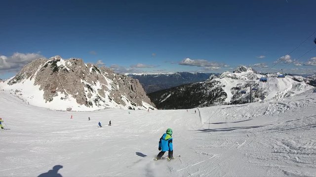 Little boy skiing. A 6 year old child enjoys a winter holiday in the Alpine resort. Stabilized footage. Slow motion.