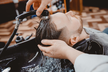 Washing hair head hairdresser, barber rinses shampoo off with water pressure