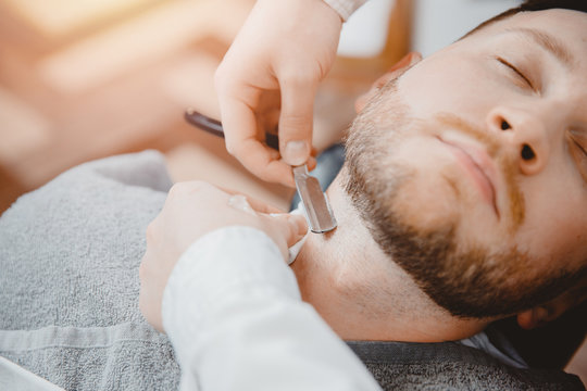 Barber process shaving razor bearded hipster man in barbershop