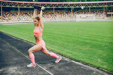 Sports girl at the stadium. Beautiful girl doing sports.The girl raises the weight