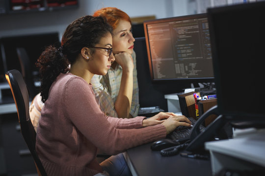 	 Two female programmers working on new project.They working late at night at the office.	