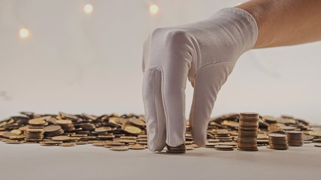 The concept of money. Columns of gold coins in the form of skyscrapers or Stonehenge. Close-up hands make up stacks of coins. Smoke. Garland.