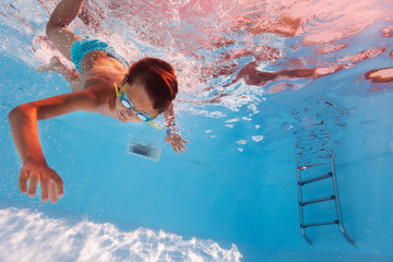 Boy swim underwater in the pool wearing googles