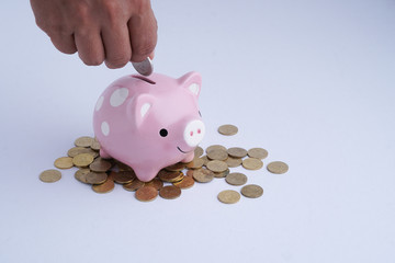 Hand insert coin into piggy bank isolated in white background. Saving and financial concept