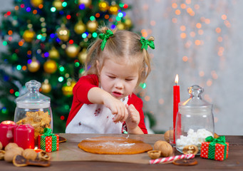 Little cute girl flour sprinkles rolled dough on the background of the Christmas tree
