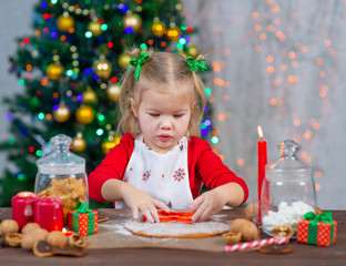 Little cute girlcuts out cookies with cookie cutters