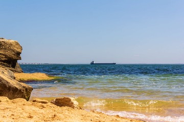 Fototapeta na wymiar landscape with a sandy beach, sea waves and a cargo ship passing through the Kerch Strait in the black sea on a Sunny summer day