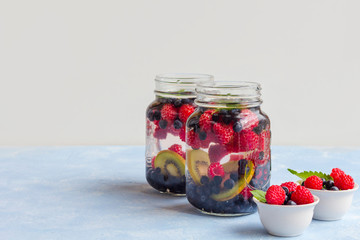 Fresh cool detox drink with raspberries, blueberries and kiwi in mason jar mug. Lemonade in a glass with a mint. The concept of proper nutrition and healthy eating. Fitness diet. Copy space for text