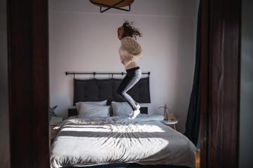 Young woman jumping in bed, happy and having fun in the morning.