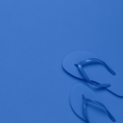Fashionable beach flip flops on blue background. Flat lay, top view, copy space. Creative beach concept, stylish summer shoes, vacation, travel. Summer background. Color of the year 2020 classic blue