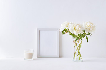 Mockup with a white frame and white peonies in a vase on a white background